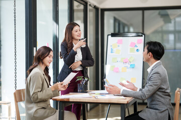 Group of Asian businesspeople sits down for a business investment planning meeting.
