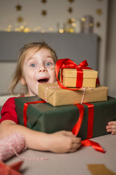 Smiling child holding Christmas presents indoors with festive atmosphere