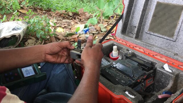 Close-up of an Indian male technician performing fiber optic fusion splicing using a splice machine to connect internet cables, showcasing telecom network installation and high-speed data infrastructu