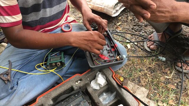 Close-up of an Indian male technician performing fiber optic fusion splicing using a splice machine to connect internet cables, showcasing telecom network installation and high-speed data infrastructu