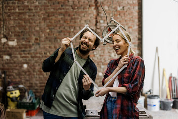 Couple smiling and planning renovation with measuring tape at construction site