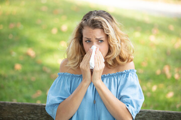 sneezing young girl with nose wiper in a park
