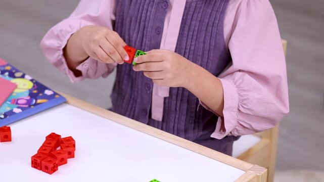 Child Assembling Colorful Math Manipulative Blocks at Desk