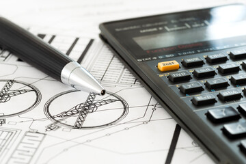Scientific calculator and a pen on detailed engineering drawings, representing technical analysis, precise calculation, problem solving, and professional design workflow.