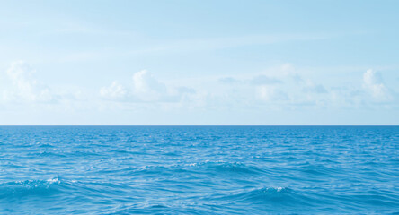 Obraz premium Calm ocean waves under serene blue sky with clouds