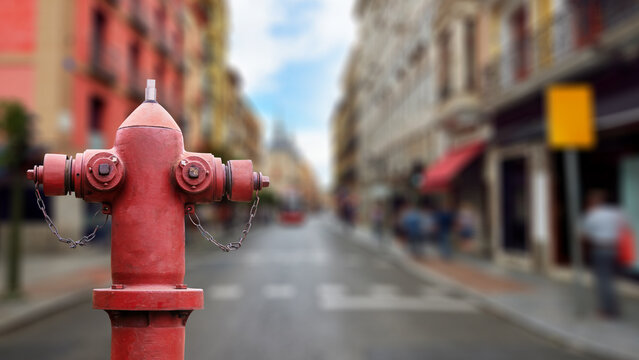 Red fire hydrant with blurred city street and buildings in the background