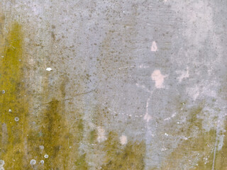 Texture of an old weathered concrete wall covered in green moss and lichen with grey patches and cracks. A rustic, gritty background perfect for industrial or vintage architectural design projects.