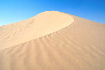 Sunset over the desert of Al Khatim in Abu Dhabi, Emirates. Golden Sand Dune desert landscape dunes with blue sky. Sand mounds formed in circular shape, beauty of natural changes over great stretches