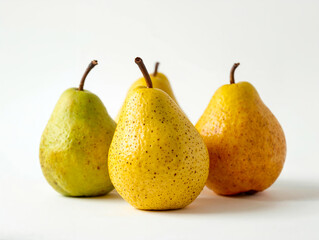 Group of four fresh yellow and green pears isolated on white background. Minimalist organic fruit composition with shallow depth of field for healthy food branding and graphic design.