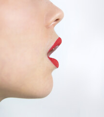 Side profile close up of woman face with red lipstick open mouth clean skin and sharp nose line creating minimalist beauty makeup concept