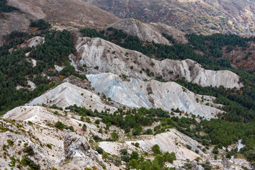Eroded white sand dunes and green pine forests create a striking contrast in the mountain valleys, displaying the unique geological formations of the Trevenque area in Sierra Nevada National Park.