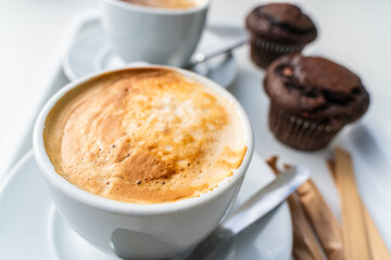 Cups of cappuccino with chocolate muffins