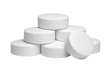 Piled, white, round pills stacked closely on a black backdrop