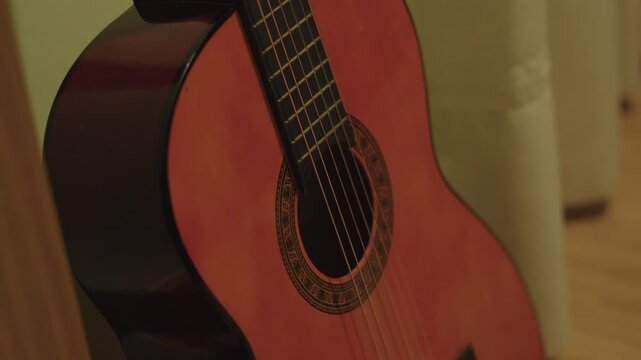 Close Up Body Of Spanish Acoustic Guitar Laying On A Yellow Wall