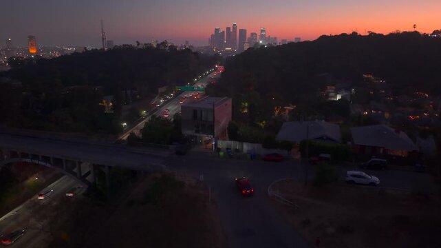 Downtown Los Angeles California, city skyline at sunset with traffic flowing along Highway toward city buildings. Highway 110. Timelapse of cars driving in traffic towards beautiful evening sunset.