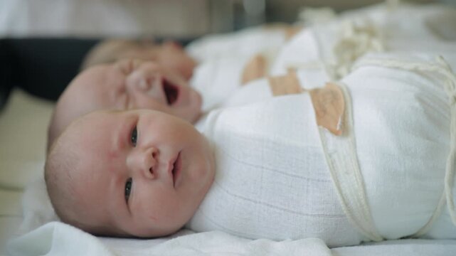 Midwife hands picking up newborn baby from hospital bassinet group