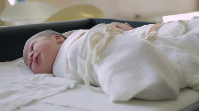 Nurse takes in hands newborn baby from hospital bassinet  in maternity ward, close up