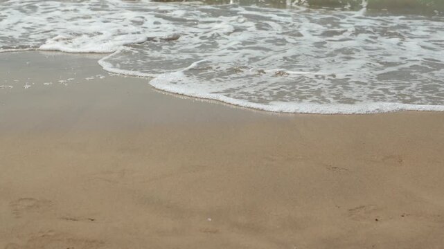 ripresa in tempo reale di piccole onde di marea che si distendono lentamente sulla sabbia di una spiaggia in Italia, di giorno, in estate