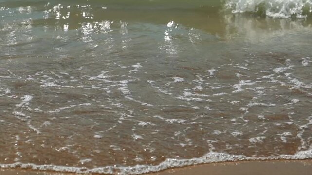 ripresa al rallentatore di piccole onde di marea che si distendono lentamente sulla sabbia di una spiaggia in Italia, di giorno, in estate