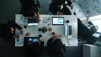 Top down aerial view of smart manager pointing at financial graph on whiteboard while diverse...