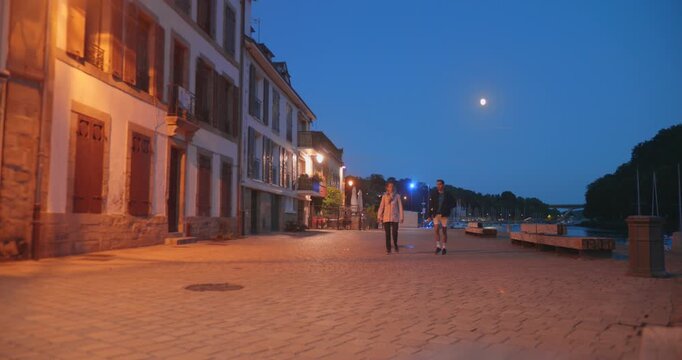 Couple walks in Auray's Saint-Goustan Port at dusk, historic charm