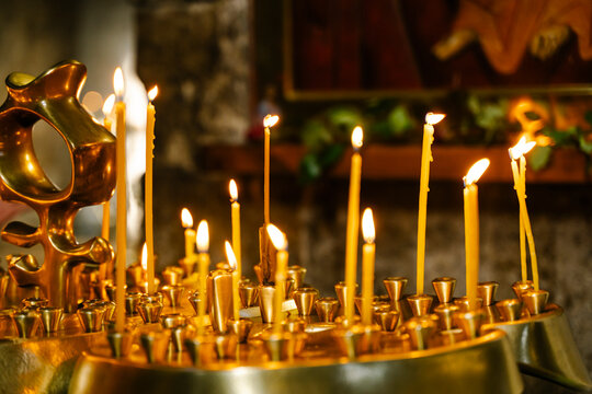 Candles in a Christian Orthodox church background. Flame of candles in the dark sacred interior of the temple
