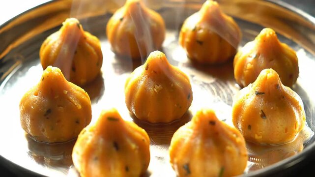 Steaming Modak sweets on silver plate for Ganesh Chaturthi festival celebration.