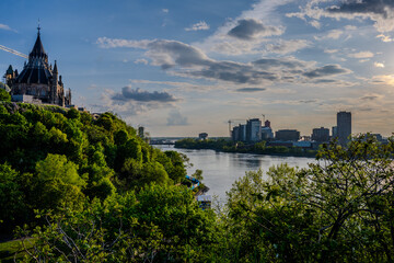 Library of Parliament above green hillside and river in Ottawa