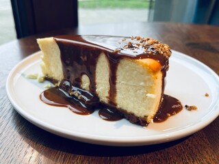Homemade style cheesecake with smooth texture and caramel glaze, decorated with nut crumble, perfect for caf&eacute; menu or dessert concept.
