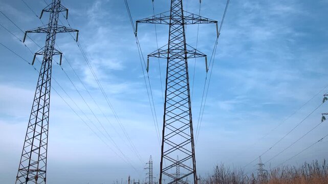 Tall Towers Stretch Across Sky, Metal Lattice Structures Stand Tall Beneath Expansive Blue Sky . Media