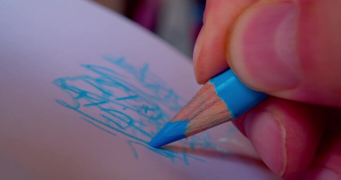 Close-up shot of hand drawing abstract pattern on paper with blue pencil