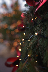 close-up of festive pine branch adorned with glowing fairy lights and red ribbon, captured in beautiful bokeh effect evoking a warm, holiday mood in a blurred background setting, delightful