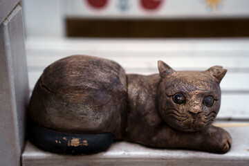weathered wooden cat sculpture resting on a white bench with intricate details, conveying a rustic charm and artistic craftsmanship, surrounded by soft light and neutral tones, detail, classic