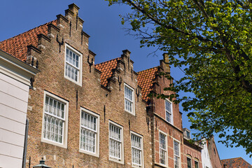Fototapeta premium Den Briel Historic Brick Buildings With Gable Roofs And White Windows In South Holland Netherlands Under Blue Sky On
