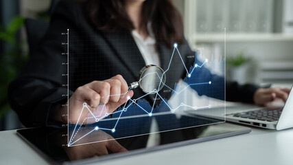 Business professional focuses on data trends using a magnifying glass on a digital tablet in a modern workspace, emphasizing financial insights and technology. Scalp