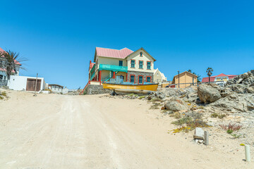 Obraz premium Colorful colonial buildings in Lüderitz, a small coastal town in Namibia, facing the Atlantic Ocean. Historic German architecture contrasts with desert landscapes, harbor views.