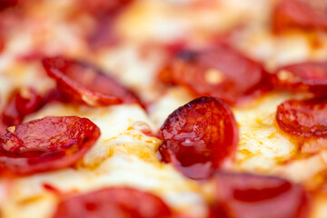 Close up photo with a shallow depth of field of pepperoni pizza with red chillies and a hot honey glaze.