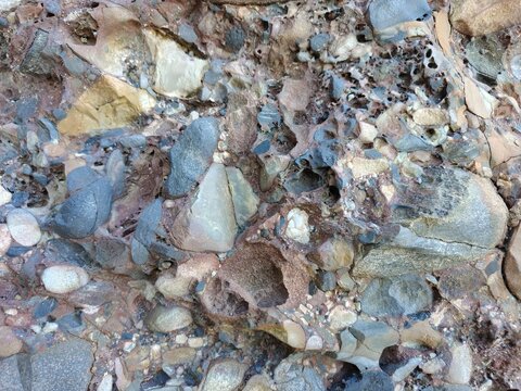 Weathered Stone Texture With Embedded Pebbles And Cracks, Natural Rock Surface Pattern, Geological Background Detail