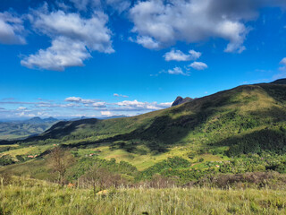 Obraz premium Sunlit Countryside Valley with Rolling Green Hills Under a Bright Blue Sky