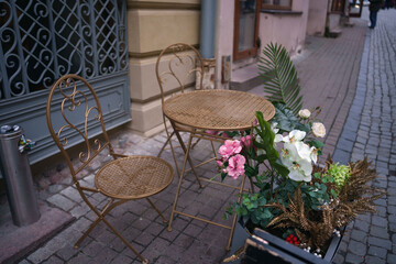 charming street cafe setting with ornate metal furniture and vibrant floral arrangements against a cobblestone path in a quaint urban alleyway, design, fence, architecture, corner, romantic