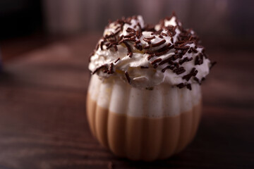 richly flavored coffee beverage in ridged glass topped with whipped cream and chocolate sprinkles on a wooden surface evoking a cozy and indulgent ambiance, dessert, savory, culinary, lush, filled