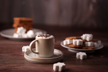 warm and cozy scene with a ceramic mug of hot cocoa adorned with chocolate shavings, surrounded by star-shaped sugar cubes and biscuits on wooden surface, indulgence, savory, stacked, sip, gourmet