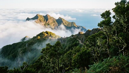 Hiker navigating a scenic mountain path with rugged peaks emerging from a sea of clouds, offering expansive ocean views and a sense of adventure on a clear day