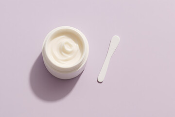 A small white jar filled with cream and an applicator stick on a soft pastel purple background, casting a subtle shadow, with a clean and minimalist composition