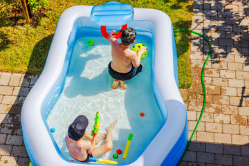 Close up top view of children playing in inflatable pool in garden area in front of villa during summer. Sweden.