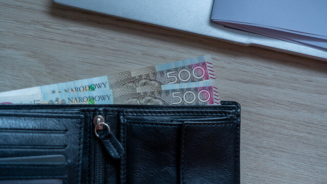 500 Zloty Banknotes with Receipt in Black Leather Wallet on Wood