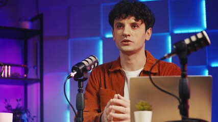 Serious male podcast creator talking into microphone, recording studio video