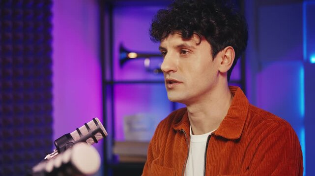 Male blogger recording true crime podcast in studio, speaking into microphone