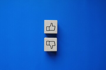 Two wooden blocks with like and dislike symbols on a blue background