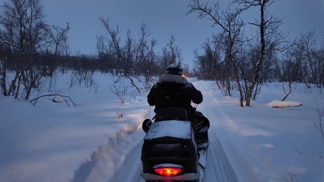 People operating snowmobile on rural countryside road in the winter.